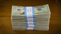 a stack of twenty dollar bills on a wooden table